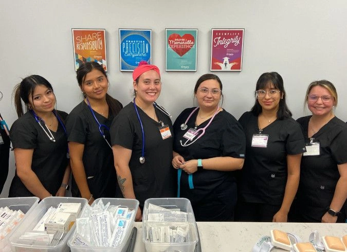 students taking a group photo behind a table of medical supplies